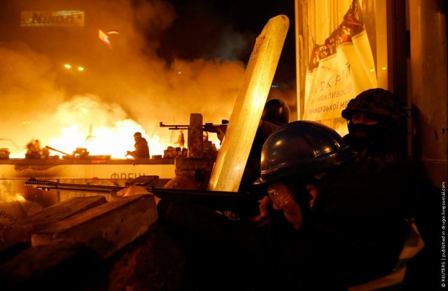 Anti-government protesters aim their weapons during clashes with riot police in Independence Square in Kiev