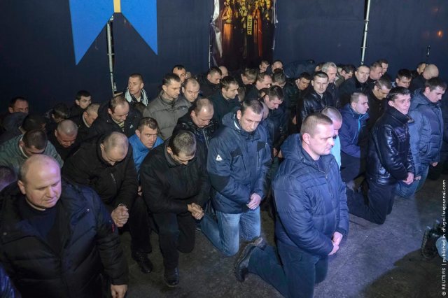 Riot police kneel as they apologize during a rally in central Lviv