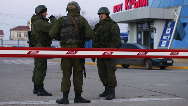 Armed men, believed to be Russian soldiers, stand outside the civilian port in the Crimean town of Kerch. Russia started a build up of armored vehicles on the Russian side of a narrow stretch of water between Russia and the Ukrainian region of Crimea, Ukrainian border guards said.