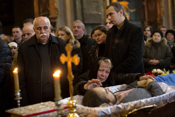 Oksana Solchanyk, center, her husband, Zinovij, left, and son Stepan mourned on Saturday in Lviv, Ukraine, over the body of their son and brother, Bohdan, 28. Photo: URIEL SINAI -NYT.