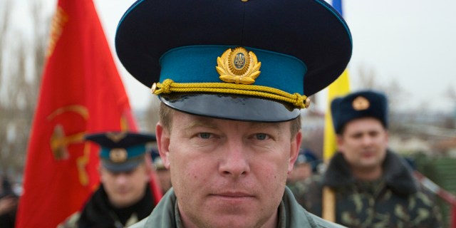 FILE - In this Tuesday, March 4, 2014 file photo, Air Force Col. Yuliy Mamchur, commander of the Ukrainian Belbek Air Base, leads his men to the base outside Sevastopol, Ukraine. The day after Crimeans voted to leave Ukraine and join Russia, a man in a black raincoat turned up at the gate of the Belbek Air Base to demand that the Ukrainian forces holed up inside surrender to Russia. The Ukrainian commander of the base came out proudly wearing his visor cap decorated with gold wings - and refused. Having withstood five days of sustained intimidation and pressure to defect from his captors, Mamchur now awaits a heros welcome in the capital, Kyiv. (AP Photo/Ivan Sekretarev, File)