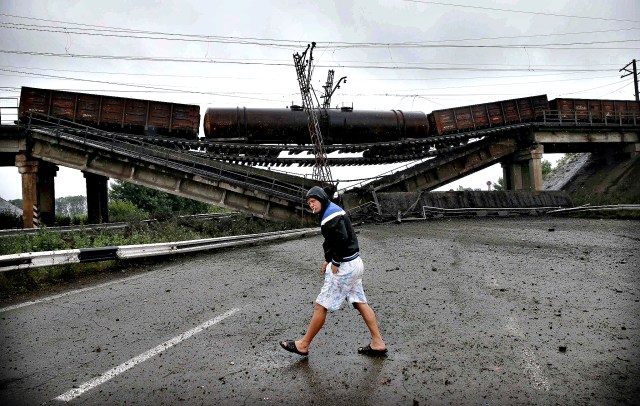 Man walking past the destroyed railroad bridge which fell over a main road leading to Donetsk, near the village of Novobakhmutivka.  REUTERS/Maxim Zmeyev 