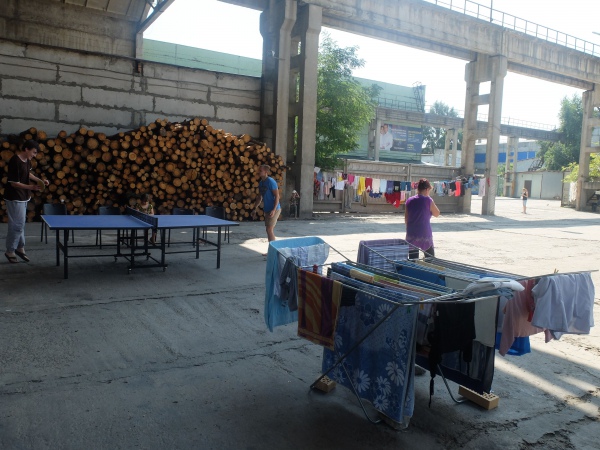 Firewood is stacked by the wall, while laundry dries in the courtyard