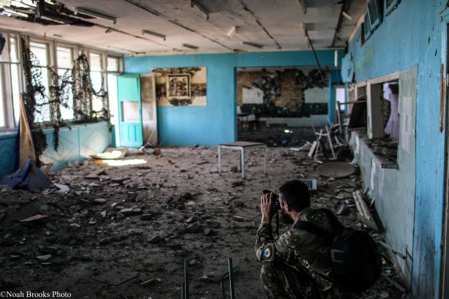 Azov photographer Ruslan photographs damage to a school. Photo: Noah Brooks
