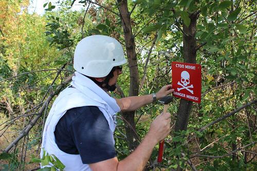 Member of International Committee of the Red Cross putting up signs warning of minefields near Berezove. Source