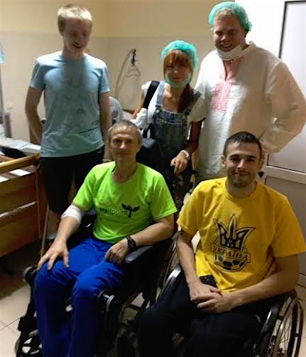 NODUS' ATO Ward 1: Volunteers Yuliya Grassby and James Clement visit wounded soldiers to talk about the war, their experiences and the future of Ukraine. Iliya Karpov (ATO volunteer participant/standing, suffered a brain trauma injury in January of 2015; he has had 3 rounds of rehabilitation at Nodus since February 2015 – was in a coma, then in a wheelchair, then used a cane – and this past summer, Iliya started his third round of rehabilitation to begin walking without a cane). Artur Kireev (officer, in yellow t-shirt) and Sergey Saliy (officer, in green t-shirt) were both wounded with spinal cord injuries. Artur graduated with a military degree. Sergey was a volunteer soldier. 